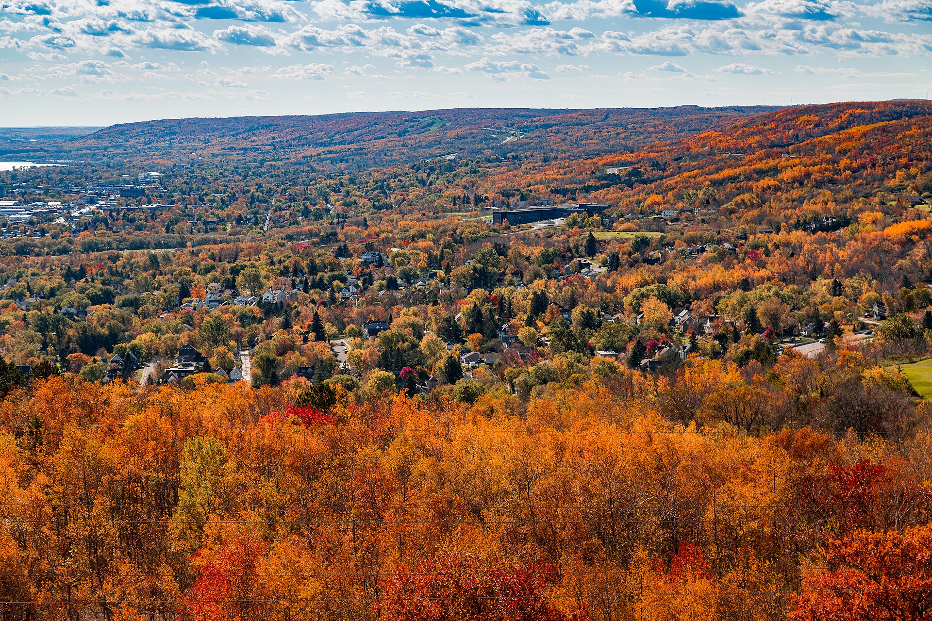 Duluth's wooded hillside neighborhoods in full fall color, seen from Enger Tower with the ridgeline behind