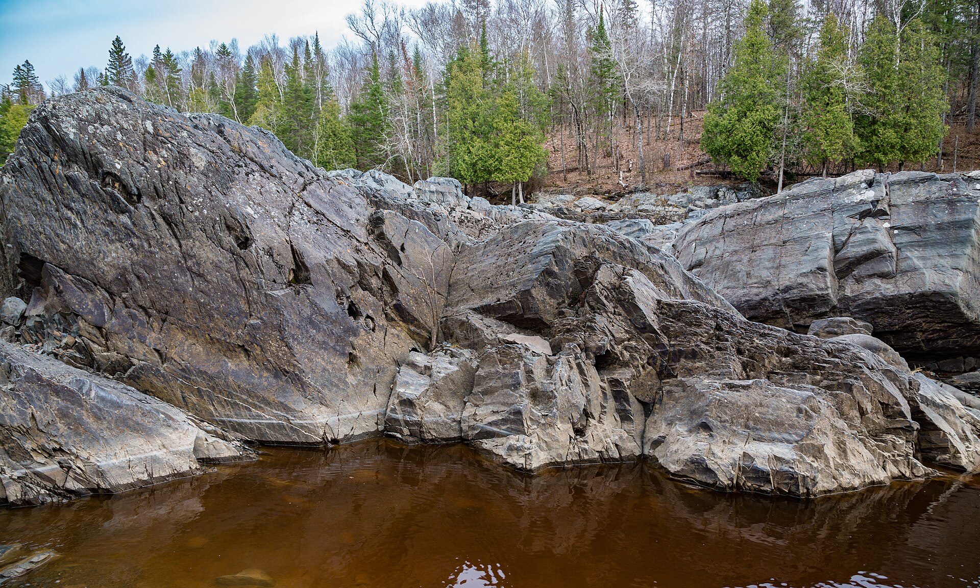 The St. Louis River winding between tilted rock beds and spring woods in Jay Cooke State Park