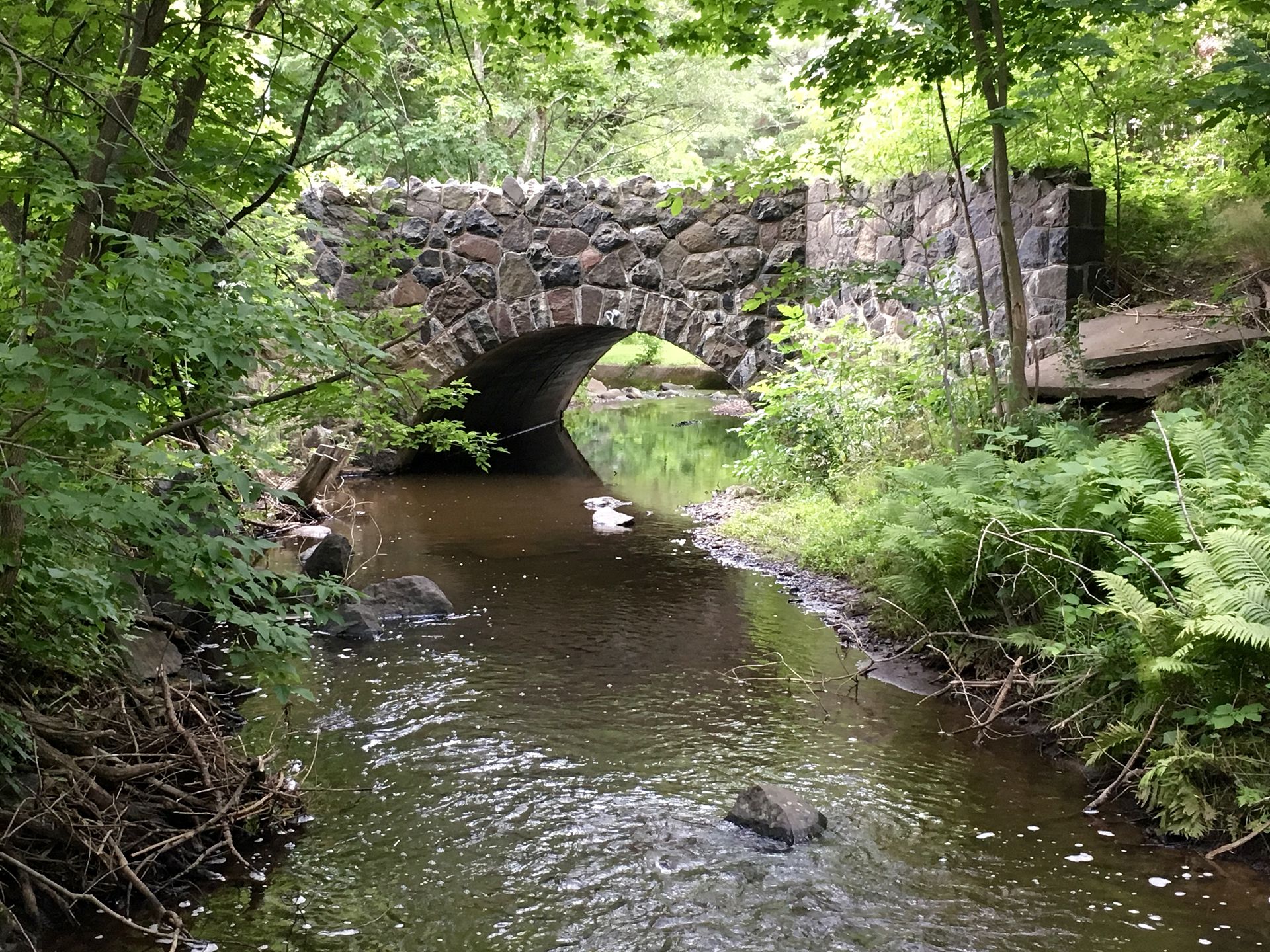 A fieldstone arch bridge over Tischer Creek in a wooded ravine in Hunter's Park, Duluth