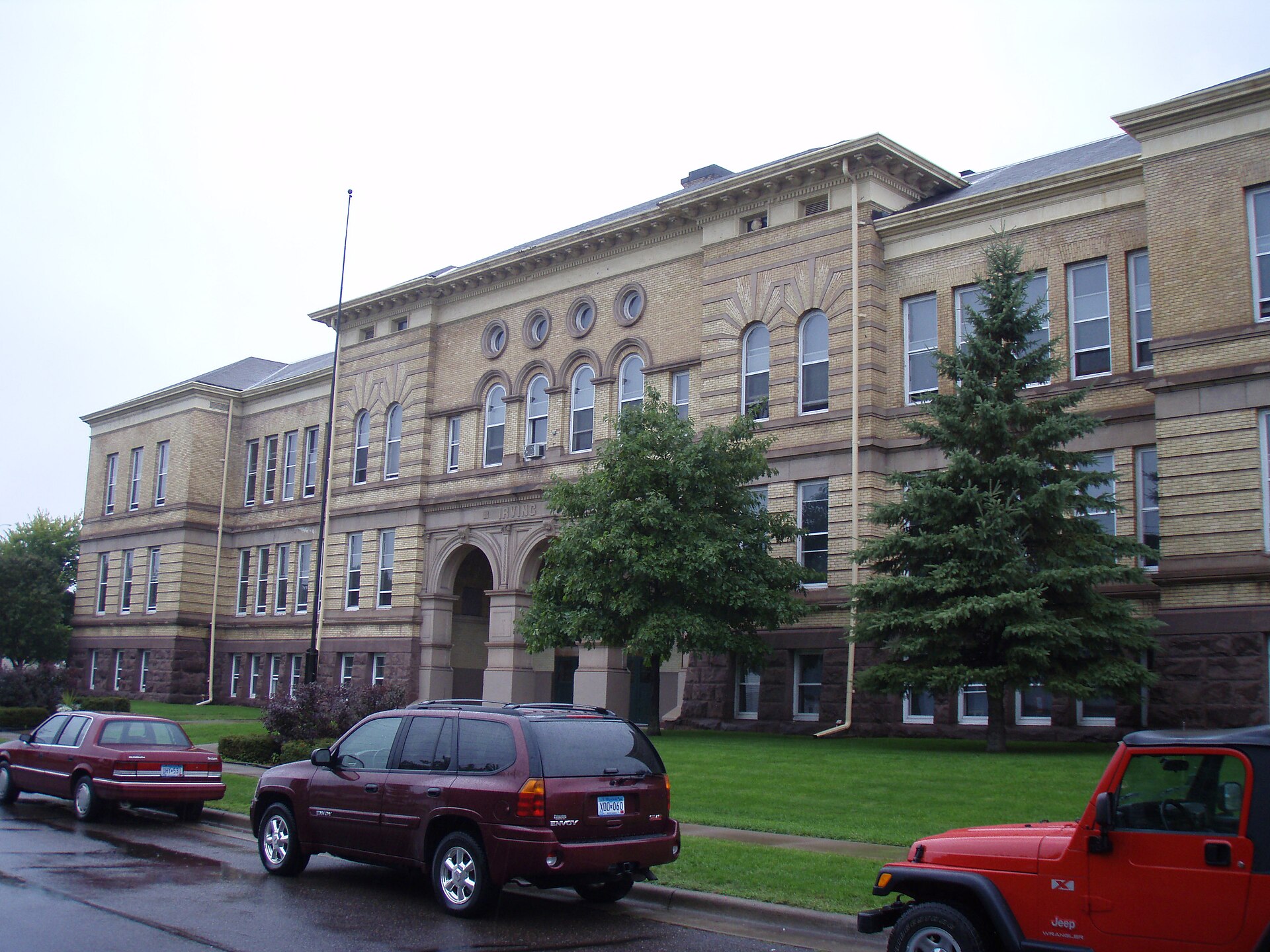 The long buff brick and brownstone front of Irving School on a flat street in West Duluth