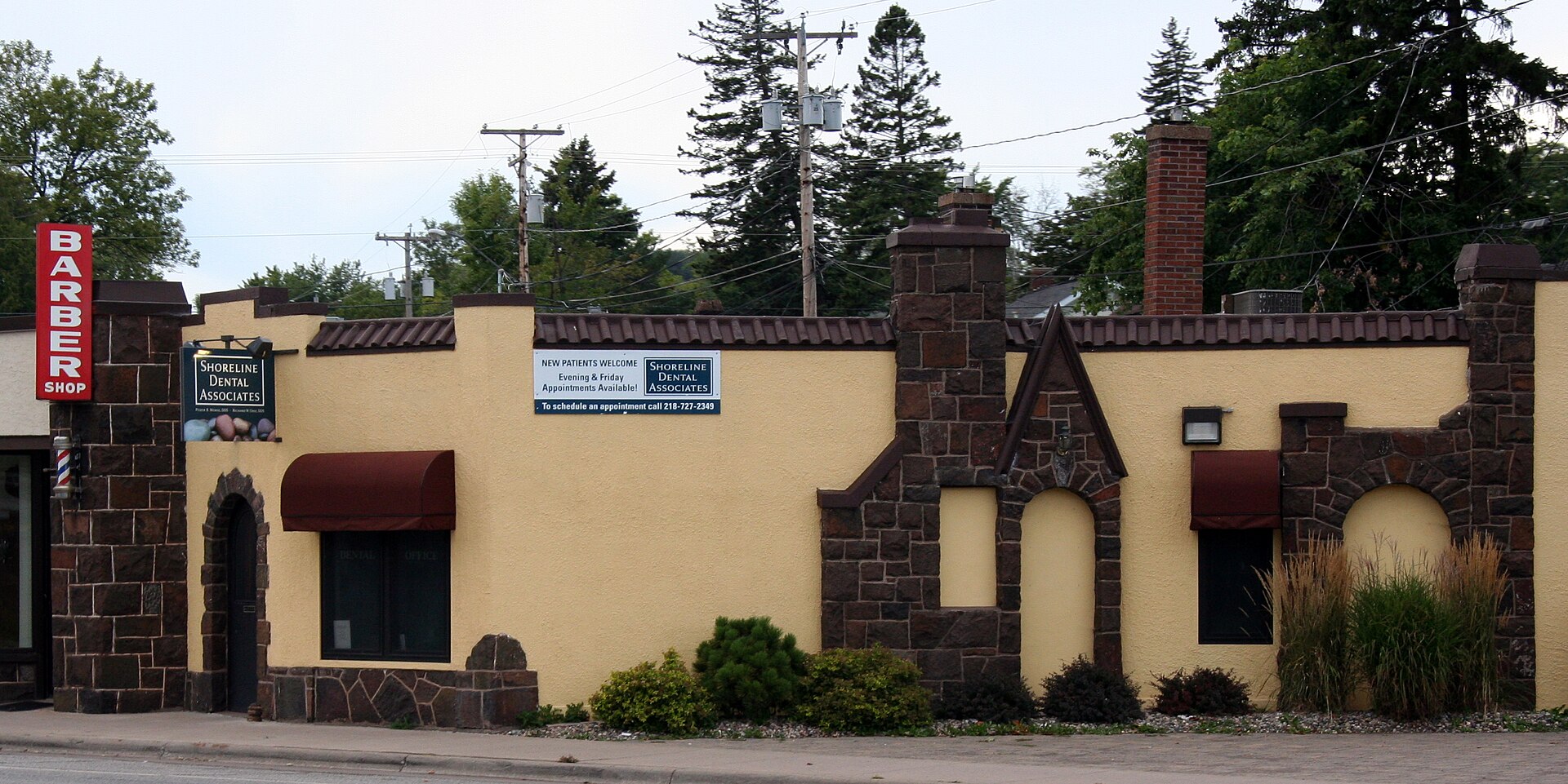 A low stone and stucco commercial building with a barber shop sign on East Superior Street in Lakeside, Duluth
