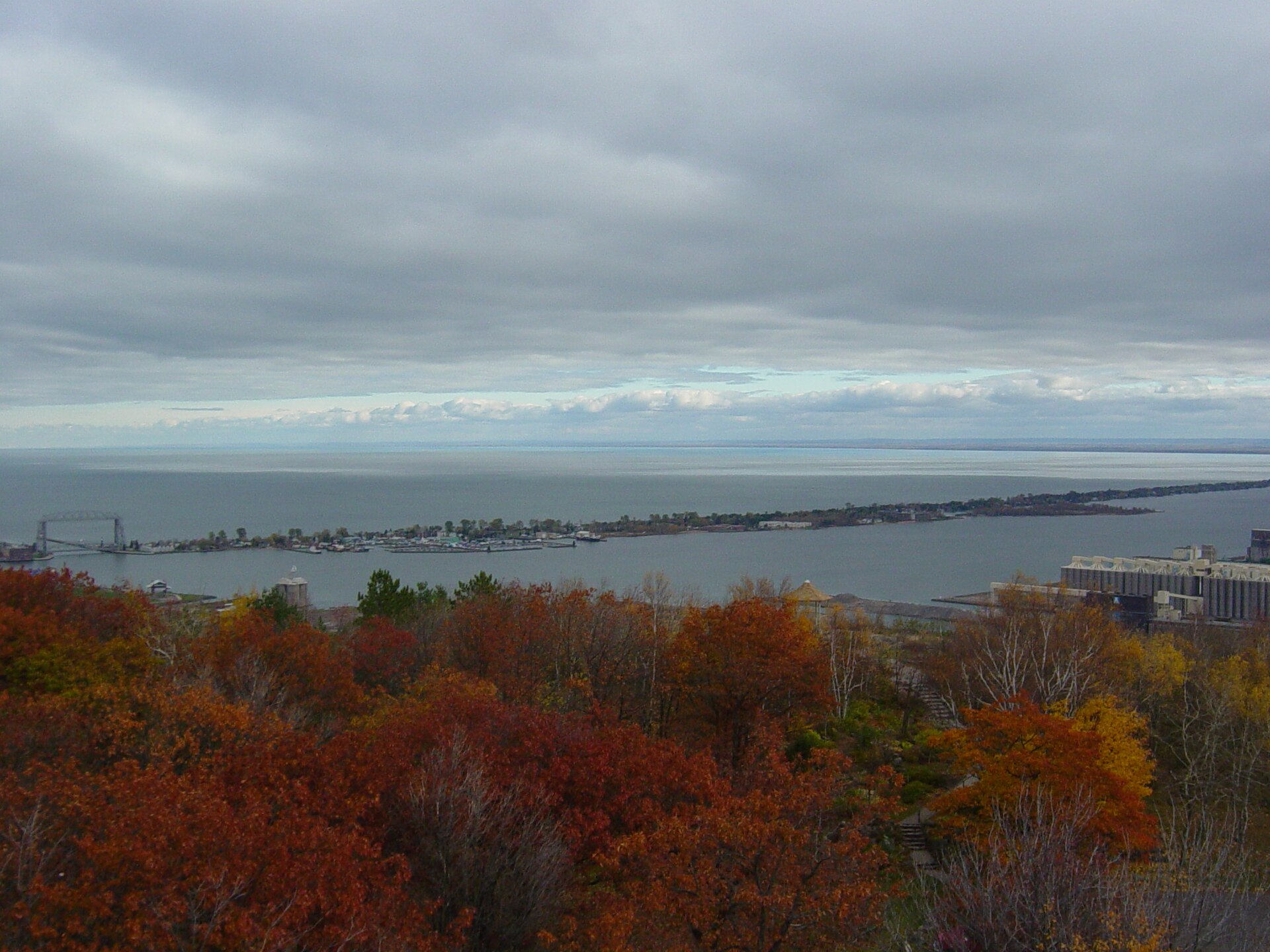 The Park Point sandbar running out into Lake Superior across the Duluth harbor, with the Aerial Lift Bridge at left and fall colors in the foreground