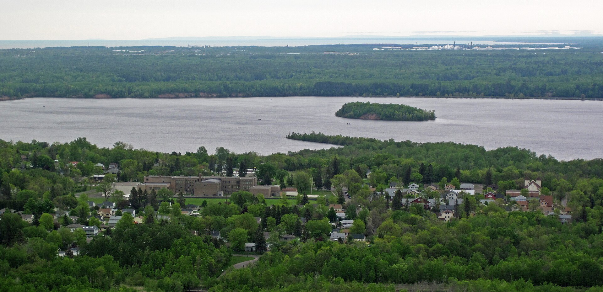 The St. Louis River running between wooded banks below a far west Duluth hillside, with a low wooded island midstream