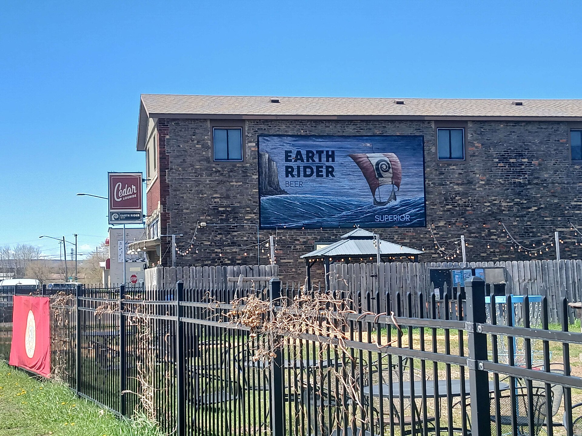 The brick side wall of the Earth Rider brewery in Superior, Wisconsin, painted with a large mural, above the Cedar Lounge beer garden